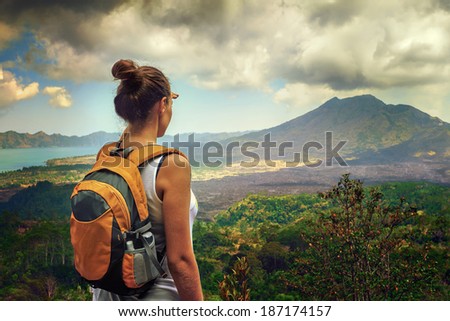 Lady tourist with a backpack standing on top of the mountain and enjoy the beautiful volcano Batur. Indonesia