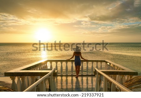 Woman on balcony looking at the beautiful sunset Woman on balcony looking at the beautiful sunset