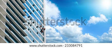 Group of workers cleaning windows on high rise building.Panoramic view