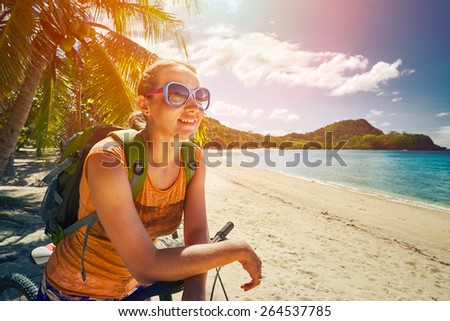 Young woman with backpack standing on the shore near his bike and looking on sea. Traveling along Asia, active lifestyle concept