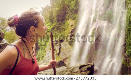 A tired but happy young tourist woman looking at the waterfall in the Central America jungles\
Ecotourism concept image travel girl