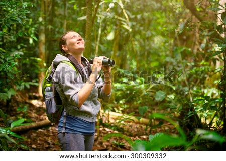 Hiker watching through binoculars wild birds in the jungle. Bird watching tours