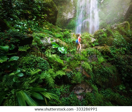 A tired but happy tourist woman looking at the waterfall in the Central America jungles\
Ecotourism concept image travel
