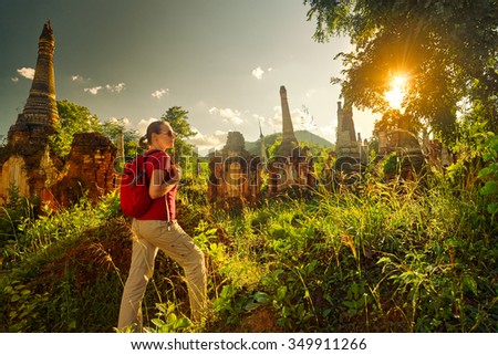 female traveler with backpack walking and looks at sunset among ancient Buddhist stupas of the temple complex  In Dein, Inle Lake. Mayanmar