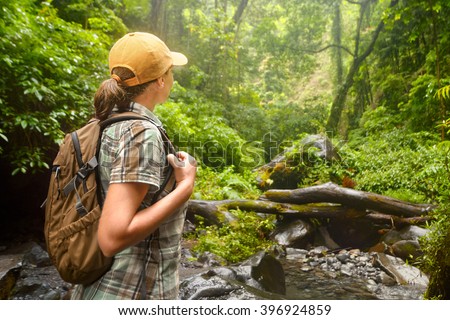 Young backpacker with backpack  traveling along rain forest. Lombok, Indonesia. Tourist hiking in the deep jungle
