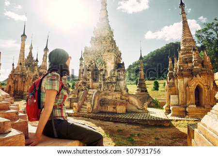 Young traveller enjoying a looking at Buddhist stupas. Burma, Asia. \
Traveling along Asia, active lifestyle concept.