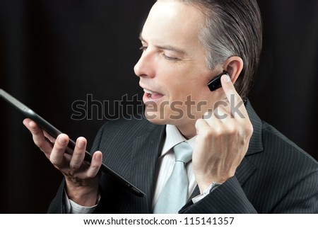 Close-up of a businessman using a tablet adjusting his earpiece headset.