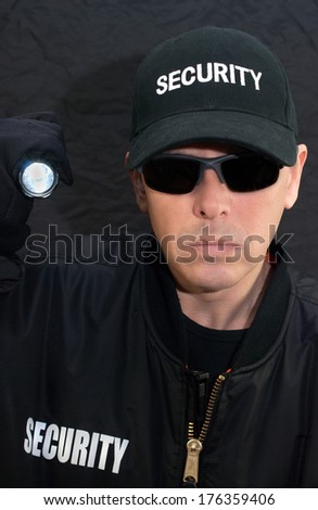 Close-up of a security guard shining a flashlight at the camera.