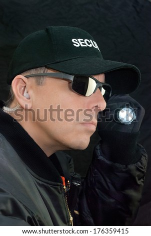 Close-up of a security guard searching with his flashlight.
