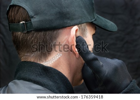 Close-up of a security guard listening to his earpiece. Shot from, over the shoulder.