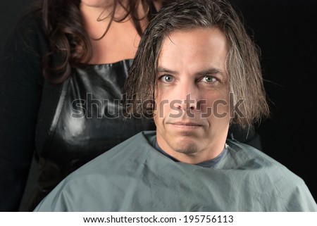 Close-up of a man, his hair newly shampooed, wearing a cape and ready for a hair cut.