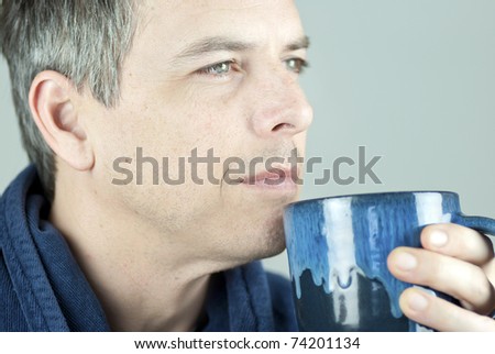 Close-up of a serene man holding his mug and looking off camera..