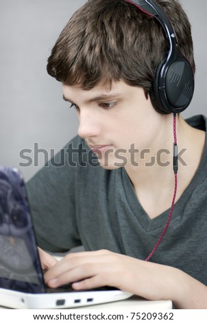 Close-up of a teen wearing headphones working on his laptop..