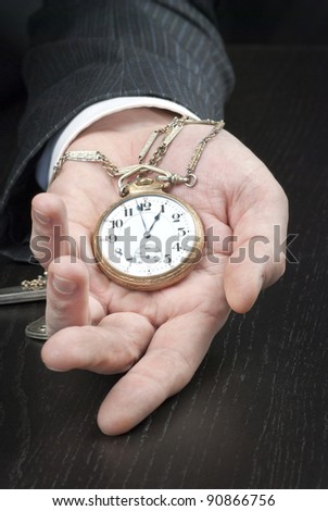 Close-up of a businessman displaying an open pocket-watch in his hand.