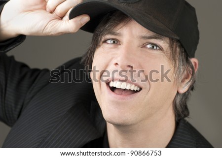 Close-up of a smiling businessman adjusting his ball cap.