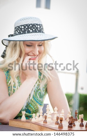 Thinking woman with straw hat in a chess game