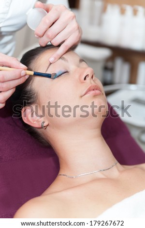 Makeup artist using a brush to apply makeup to woman\'s eyelids