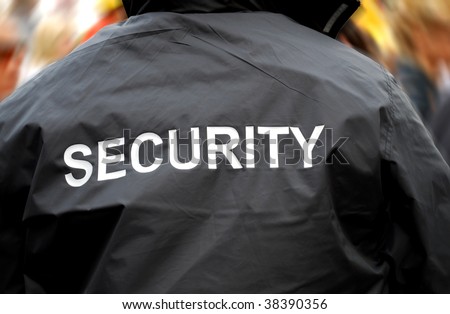 back of a security guard in front of blurred crowd