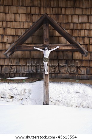 cross with jesus christ figure at a bavarian farmhouse in winter