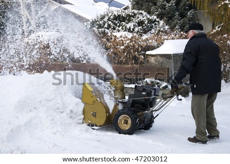 senior man with snow blower in wintertime