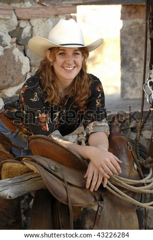 Cowgirl in stone barn with Hat, saddle, and chaps
