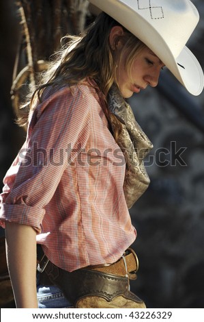 stock photo Cowgirl in a stone barn with her chaps and pink shirt