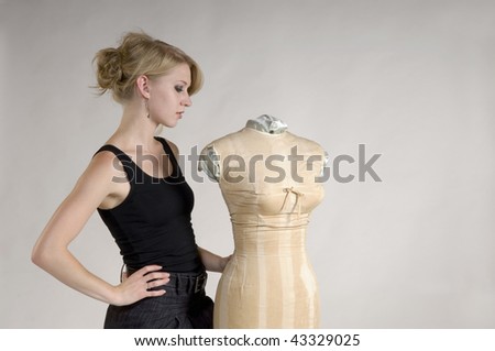 Fashion designer in black tank top and skirt works on a project with vintage mannequin