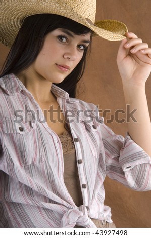 A cowgirl wearing a straw hat in studio