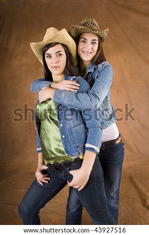 Twin cowgirls wearing jean jackets with straw hats