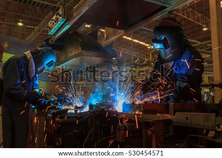 workers are welding assembly car parts in automotive industrial factory with protection mask