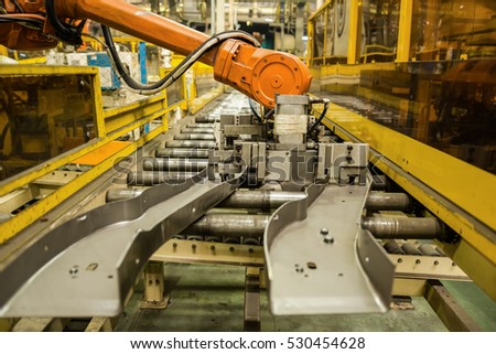 Robot arms handle tool keep automotive part to conveyor line.