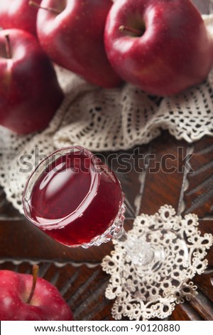 Red juice in a small glass and red apples on background - Shallow depth of field