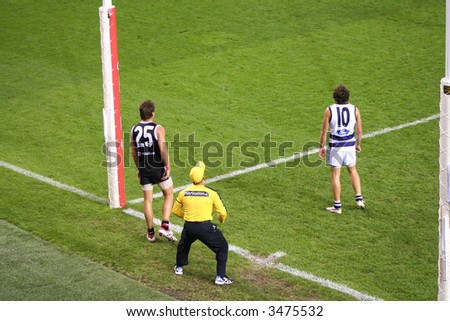 Editorial,Australian rules football geelong and the saints indoor under lights. Umpire gets in position for score