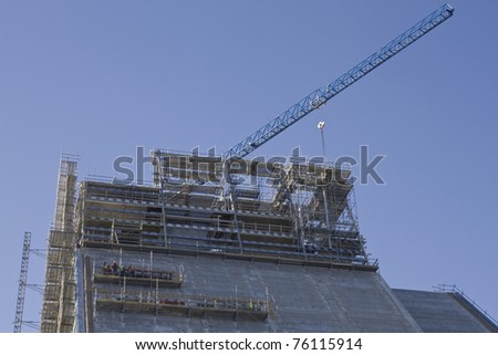 Construction of new building with one crane in background and workmen.