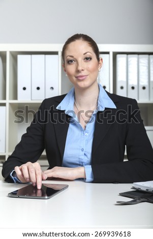 Female manager types on tablet pc screen while she has a coffee break