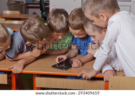 six school kids are playing an interactive game on a tablet pc