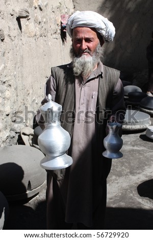 BAHARAK, AFGHANISTAN - JUNE 1: Elderly man in turban exhibits the jug he has made from recycled metal on June 1, 2010 in Baharak, Afghanistan