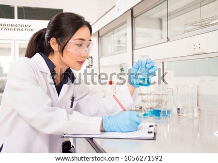 Interior of clean modern white medical or chemical laboratory background. Scientist working at lab with test tubes/flasks. Laboratory concept with Asian woman chemist/researcher.