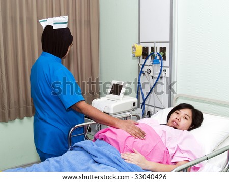 Nurse checking pregnant women tummy at hospital
