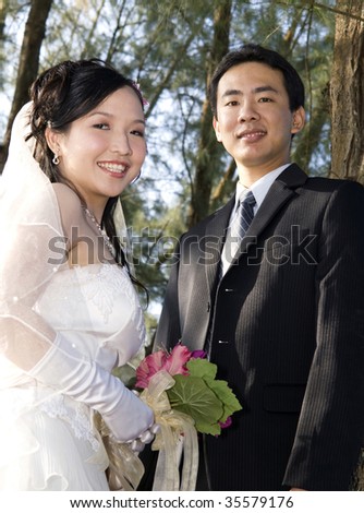 Wedding couple holding flower bouquet smiling in the golf course