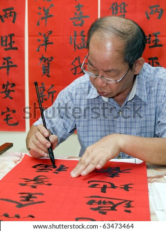 Man writing Chinese calligraphy on red paper