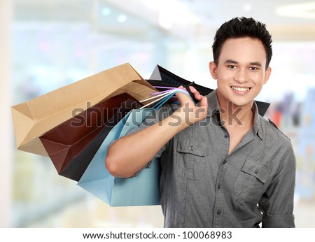 Young man shopping in the mall with many shopping bags in his hand