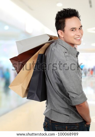 Young man shopping in the mall with many shopping bags in his hand