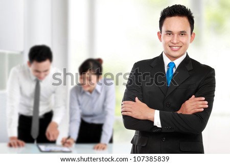 Happy young business man looking at camera with satisfaction at office
