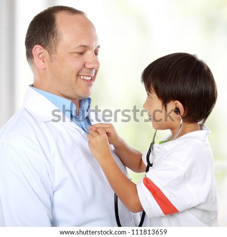 Portrait of a doctor having fun using stethoscope with his young kid patient