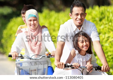Happy asian family riding bikes in the beautiful morning