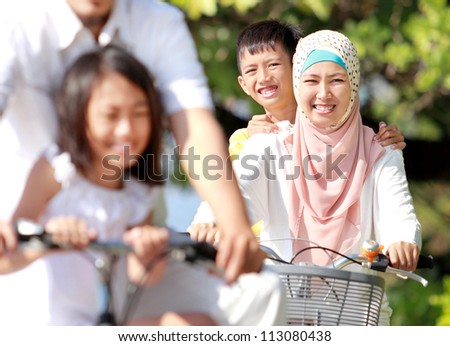 Happy muslim family riding bikes together in beautiful sunny day