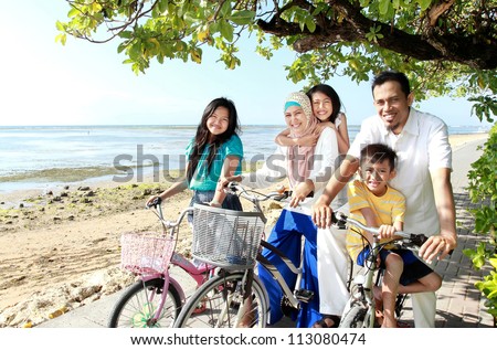 Happy asian family riding bikes in the beautiful morning at the beach