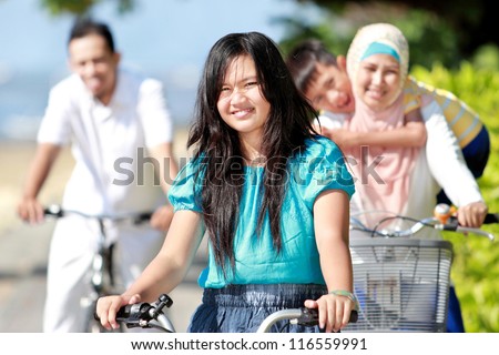 Happy asian family riding bikes in the beautiful morning at the beach