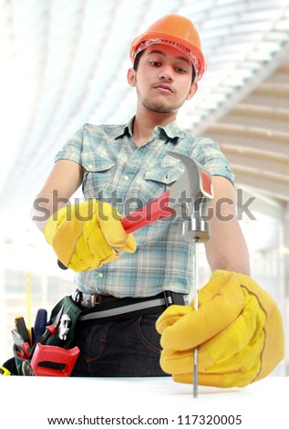 Portrait of an happy worker using hammer at construction sites